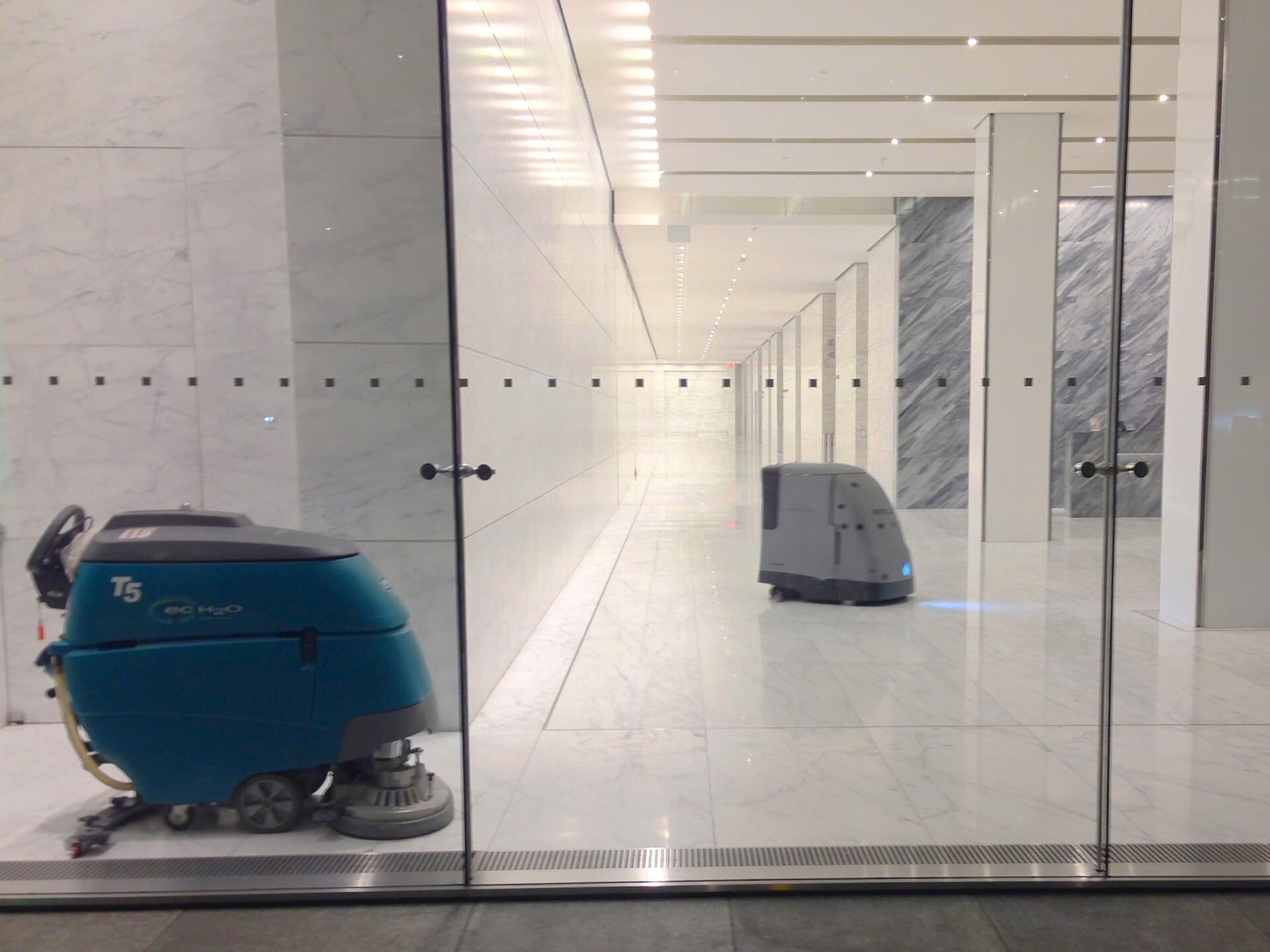 Walk-behind and robotic floor scrubbers side by side