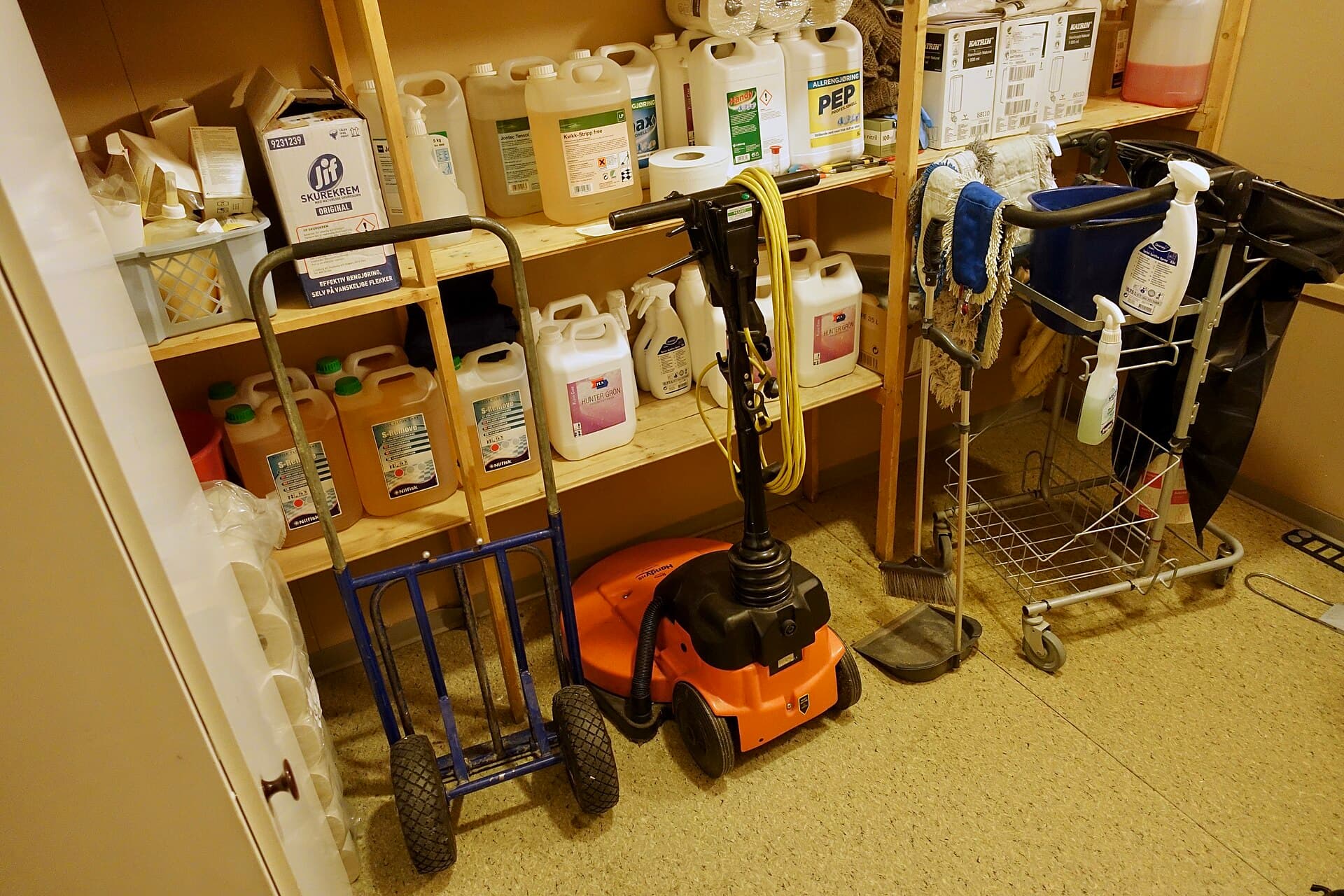 Cleaning trolley, mop heads and chemicals in a school cupboard